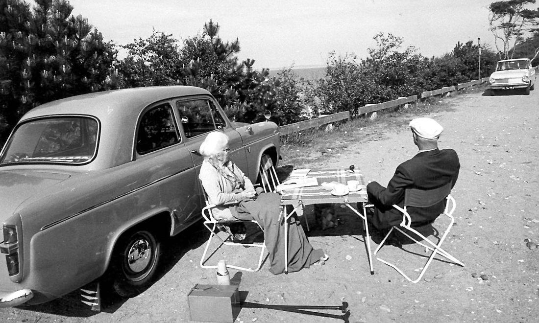 Et ældre ægtepar drikker kaffe foran deres Volvo Amazon. Tiden kunne godt føles lang, når man havde forladt arbejdsmarkedet, men var det kommunernes opgave at gøre noget ved det?