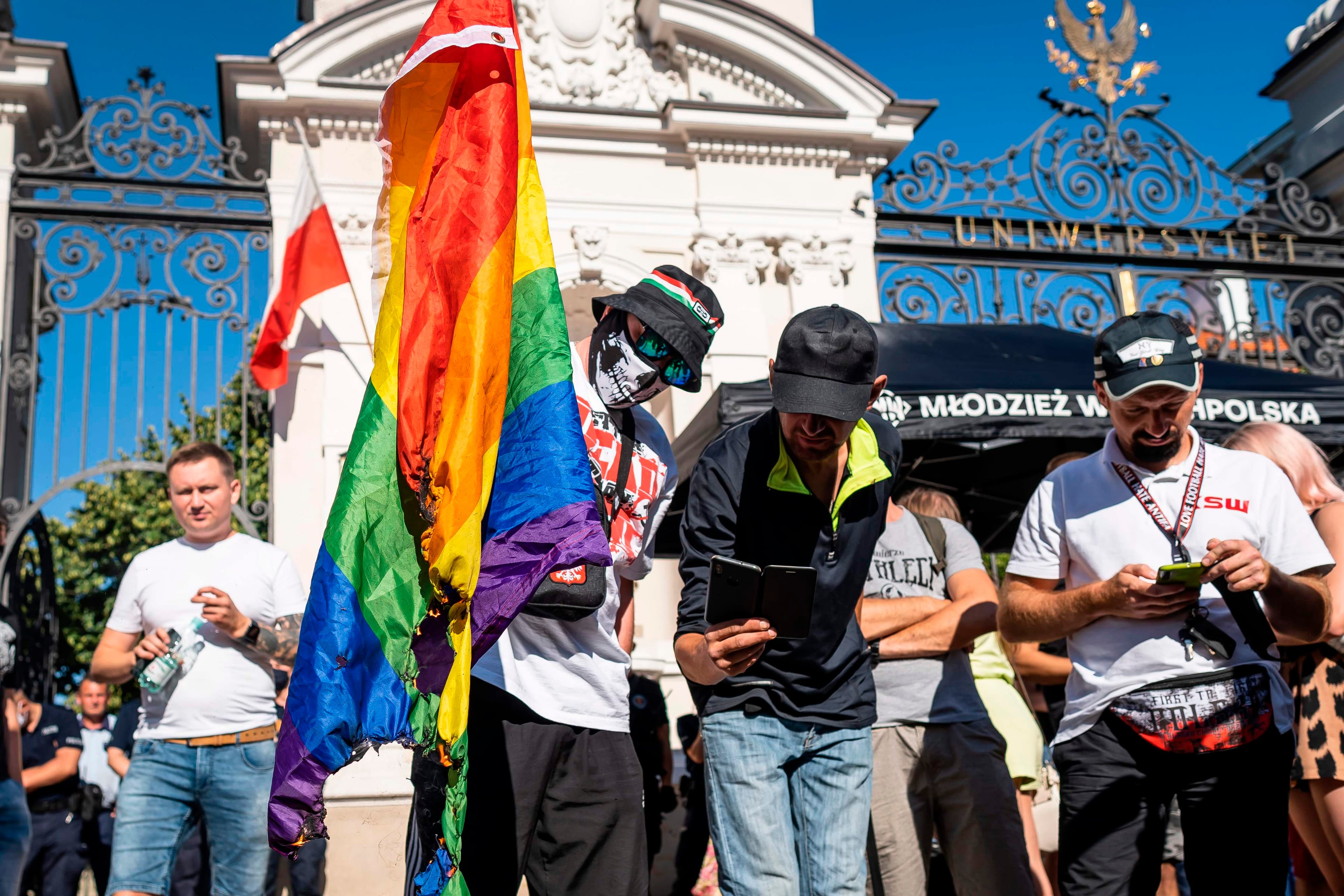 Demonstranter brænder et regnbueflag af i en anti-LGBTQ+ demonstration foran Warszawa Universitet.